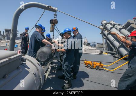 LES marins DE LA MER DES PHILIPPINES (11 mai 2022) chargent une torpille sur le fantail du destroyer de missile guidé de classe Arleigh Burke USS Benfold (DDG 65). Benfold est affecté au Commandant de la Force opérationnelle (CTF) 71/Destroyer Squadron (DESRON) 15, le plus grand DESRON déployé à l’avant de la Marine et la principale force de surface de la flotte américaine 7th. Banque D'Images