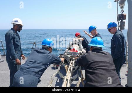 LES marins DE LA MER DES PHILIPPINES (11 mai 2022) chargent une torpille sur le fantail du destroyer de missile guidé de classe Arleigh Burke USS Benfold (DDG 65). Benfold est affecté au Commandant de la Force opérationnelle (CTF) 71/Destroyer Squadron (DESRON) 15, le plus grand DESRON déployé à l’avant de la Marine et la principale force de surface de la flotte américaine 7th. Banque D'Images