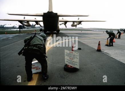 Les membres de l'escadre tactique de 50th vêtus d'engins de guerre chimique déchargent une cargaison nucléaire simulée d'un avion C-130 Hercules pendant l'exercice de guerre chimique Salty Mace. Le C-130 provient du Escadron de transport aérien tactique 37th, à la base aérienne Rhein-main, en Allemagne de l'Ouest. Objet opération/série: BASE DE MACE SALÉE: Base aérienne de Hahn pays: République fédérale d'Allemagne (FRG) Banque D'Images