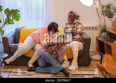 Bonne mère africaine et fille ayant plaisir à jouer à des jeux vidéo en ligne à la maison - divertissement de jeu et concept de technologie Banque D'Images