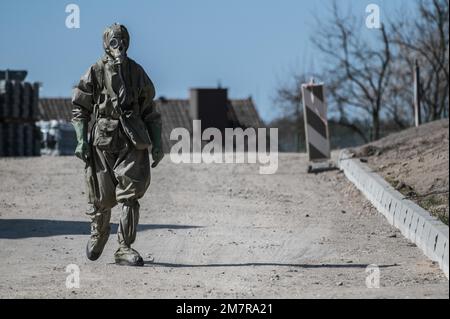 Homme vêtu d'un costume chimique marchant dans la rue au début de la pandémie COVID-19, province de Warmia-Masuria, Pologne Banque D'Images