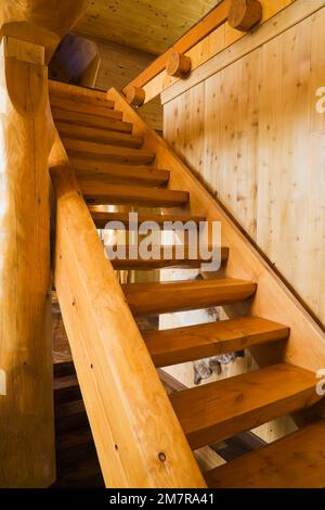 Escalier en bois menant à l'étage à l'intérieur de la maison en bois de cèdre rouge fabriquée à la main. Banque D'Images