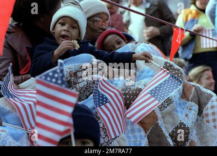 Deux petits enfants enveloppés dans une courtepointe, tenue par l'un de leurs parents, brandirent un drapeau américain en attendant que le président Ronald Reagan passe le jour de l'inauguration. Base: Washington État: District de Columbia (DC) pays: Etats-Unis d'Amérique (USA) Banque D'Images