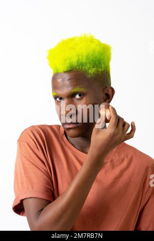 Un homme noir androgyne posant sur le maquillage, concept LGTBI, appliquant rouge Banque D'Images