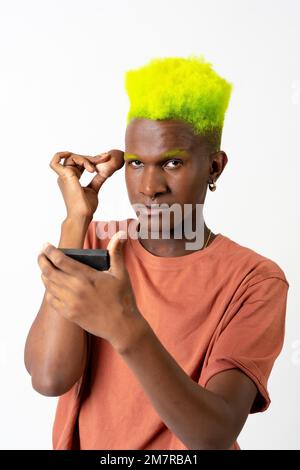 Un homme noir androgyne posant sur le maquillage, concept LGTBI, portrait appliquant le fard à joues Banque D'Images