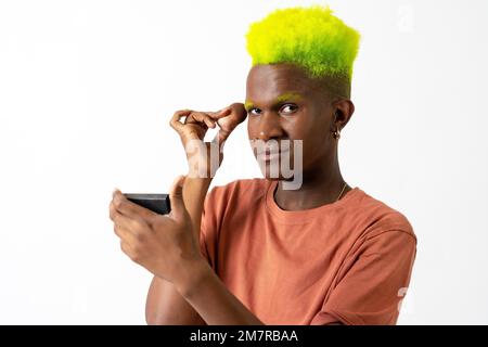 Un homme noir androgyne posant sur le maquillage, concept LGTBI, portrait appliquant le fard à joues Banque D'Images