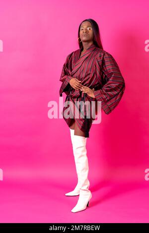 Homme ethnique noir dans un studio, concept LGTBI, portrait portant un kimono rouge et des talons hauts blancs Banque D'Images