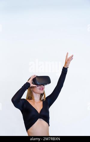 Femme portant des lunettes de réalité virtuelle sur fond blanc, concept futuriste, métaverse, photo verticale, espace de copie Banque D'Images