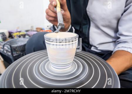 Artisans peignant et décorant des produits céramiques dans une usine de poterie à Fès, au Maroc, en Afrique du Nord Banque D'Images