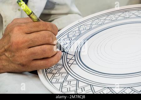 Artisans peignant et décorant des produits céramiques dans une usine de poterie à Fès, au Maroc, en Afrique du Nord Banque D'Images