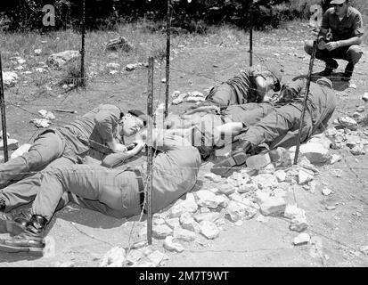 CPT Jean J. Deslauriers du Canada (port de béret) aide à transporter un patient, sur une portée, sous un fil barbelé lors d'un exercice d'entraînement sur le terrain du cours avancé d'officiers médicaux de l'Armée de terre au Camp Bullis. Base: Fort Sam Houston, San Antonio État: Texas (TX) pays: États-Unis d'Amérique (USA) Banque D'Images