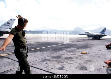 Un homme d'équipage au sol place un F-16 Fighting Falcon en position de stationnement pendant l'exercice COPE ELITE '81. L'aéronef provient du 428th Escadron d'appui tactique, 474th Escadre d'appui tactique. Objet opération/série: COPE ELITE '81 base: Marine corps Air Station Kaneohe État: Hawaii (HI) pays: États-Unis d'Amérique (USA) Banque D'Images