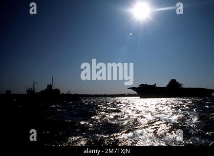 Une vue silhouetée du porte-avions anti-sous-marin de soutien de la guerre ex-USS INTREPID (CVS-11) et du remorqueur qui le tracte. L'INTREPID est en route vers Bayonne, N.J., pour être réaménagé et ouvert au public comme musée à New York. Base: New York État: New York (NY) pays: Etats-Unis d'Amérique (USA) Banque D'Images