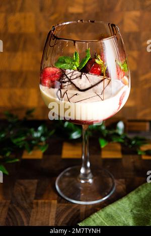 Tiramisu fraise dans un grand verre à vin. Dessert italien composé d'œufs, sucre, fromage mascarpone, fraises, biscuits Savoyardi. Décoration avec bitt Banque D'Images