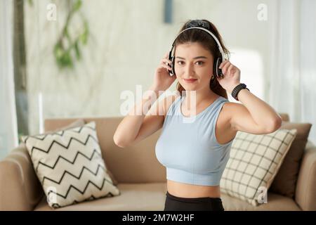 Portrait d'une jeune femme positive portant un casque pour s'entraîner à la maison Banque D'Images