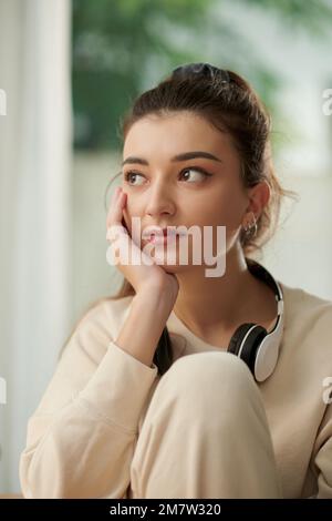 Portrait d'une jeune femme mélancolique qui réfléchit aux idées après avoir écouté de la musique à la maison Banque D'Images