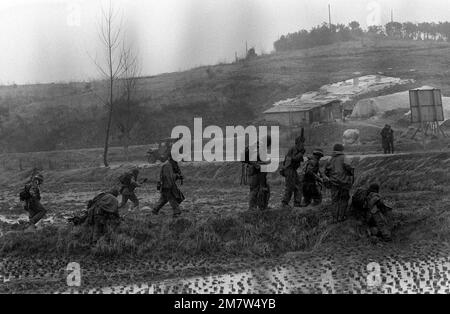 Les membres du bataillon 1st, 21st infanterie, 25th division d'infanterie, se déplacent à travers des rizières dans une attaque contre les forces orange 'ennemiant' pendant l'entraînement conjoint de Corée du Sud/États-Unis ESPRIT d'ÉQUIPE '82. Sujet opération/série: TEAM SPIRIT '82 base: Suwon pays: Corée Banque D'Images