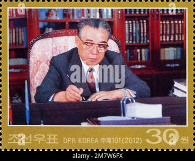 Timbre-poste nord-coréen de 2012 représentant Kim il Sung assis à un bureau écrivant ses mémoires, d'une valeur de 30 won. Banque D'Images