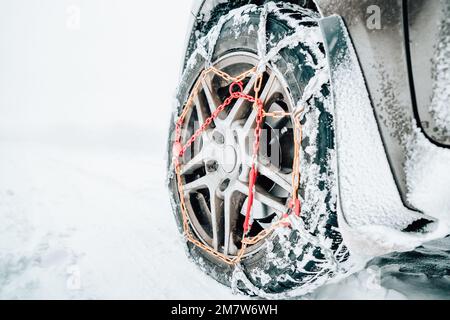 Libre de chaînes à neige montée sur une roue de voiture enneigée avec copie grand espace sur sa gauche. Banque D'Images