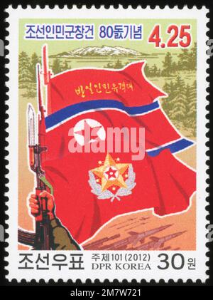 Timbre-poste nord-coréen de 2012 commémorant le 80e anniversaire de l'armée populaire coréenne, représentant des drapeaux, un fusil et le mont Paektu. Banque D'Images
