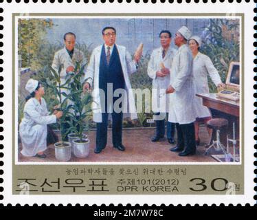 Timbre-poste nord-coréen de 2012 représentant Kim il Sung en visite dans un laboratoire pour son 100e anniversaire de naissance. Banque D'Images