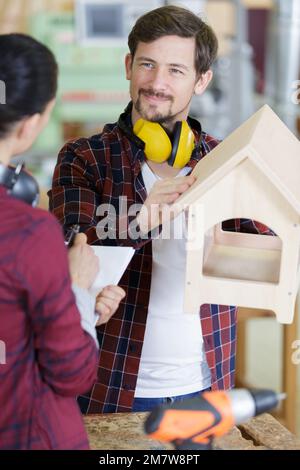 homme montrant un collègue un birdhouse en bois Banque D'Images