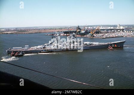 Vue aérienne à tribord du navire DE guerre IOWA (BB-61) déplacé par des remorqueurs de l'amarrage dans le stockage de mothball en vue de la modernisation, de la réactivation et de la remise en service en janvier 1985. Base: Philadelphie État: Pennsylvanie (PA) pays: Etats-Unis d'Amérique (USA) Banque D'Images