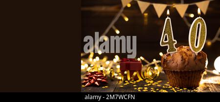 Numéro 40 anniversaire bougie dans le cupcake contre les lumières et le fond en bois. Copier l'espace. Bannière Banque D'Images