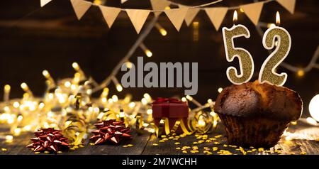 Numéro 52 bougies dorées festives dans un gâteau, arrière-plan de vacances en bois. cinquante-deux ans depuis la naissance. le concept de célébrer un anniversaire, Banque D'Images