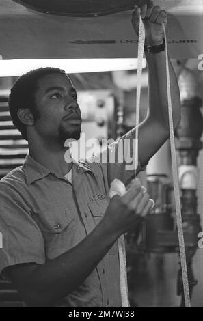 Radioman Wayne McIntosh vérifie un ruban perforé dans la salle centrale de la radio du destroyer de missile guidé USS HOEL (DDG 13). Base : USS Hoel (DDG 13) Banque D'Images