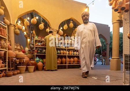 L'homme omanais en robe traditionnelle de la vaisselle marche à travers Nizwa Souq, Oman Banque D'Images
