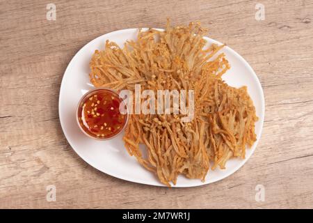 Champignons à aiguille dorés frits avec sauce douce et épicée Banque D'Images