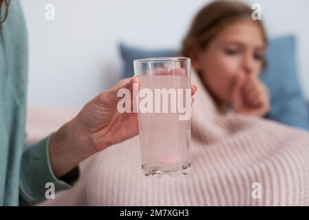 Le comprimé effervescent est dissous dans un verre d'eau - c'est un médicament pour une fille avec un rhume. Banque D'Images