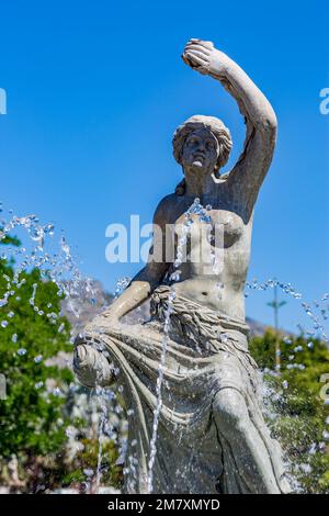 Statue féminine dans la fontaine avec jets d'eau près de celle-ci, vue ensoleillée sur la source depuis 'Parque de la Batería' à Torremolinos, Málaga, Espagne Banque D'Images