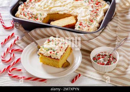 Tranche de gâteau à la feuille de vanille avec glaçage à la crème fouettée, garnie de saupoudrés du nouvel an sur une pelle à gâteau sur une assiette blanche Banque D'Images