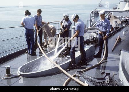 Des membres de l'équipage à bord du navire DE guerre DU NEW JERSEY (BB-62) glissent la chaîne d'ancrage au fur et à mesure qu'elle est tirée par le trou de l'aune par le ventreau. Après avoir récemment terminé les rénovations et la modernisation, le NEW JERSEY subit des essais en mer et devrait être réactivé en janvier 1983. Pays : Océan Pacifique (POC) Banque D'Images