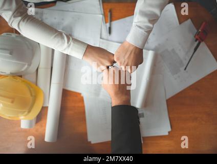 Équipe de collaboration de jeunes hommes et femmes asiatiques ingénieurs, architectes poing bosse montrer la force travail d'équipe après la réunion, discuter, conception, planing, af Banque D'Images