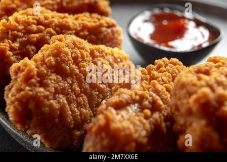 Filet de poulet frit sur fond sombre. Ailes de poulet frites comme dans le KFC à la maison gros plan. Banque D'Images