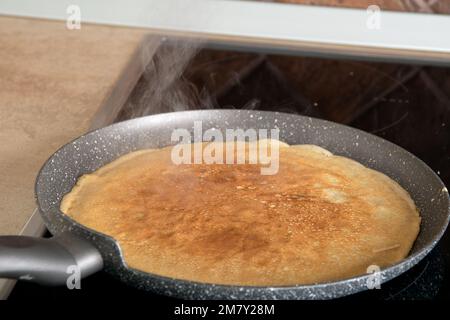 photo d'une fine crêpe friture sur une poêle à crêpes dans la cuisine Banque D'Images