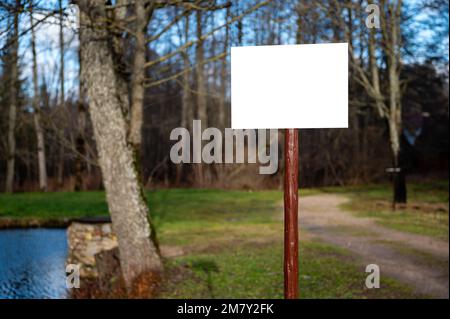 Tableau d'information vide sur un poteau en bois sur la forêt. Maquette, panneau d'avertissement, panneau d'avertissement Banque D'Images