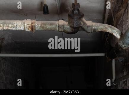 Communication de plomberie sur fond flou de ténèbres dans le sous-sol de la maison avec éclairage local Banque D'Images