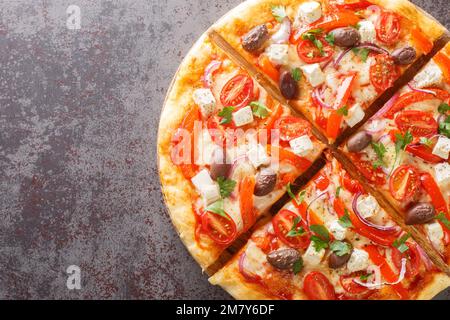 Pizza grecque maison avec feta, poivrons rouges rôtis, olive, tomate, oignons en gros plan sur une table en bois. Vue horizontale du dessus Banque D'Images