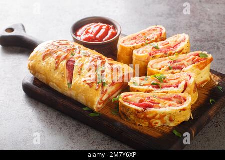 Italien stromboli, délicieux rouleau de pizza rempli de saucisse et de jambon sur le panneau de bois sur la table. Horizontale Banque D'Images