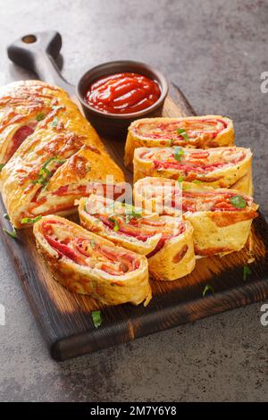 Stromboli Pizza pâte maison chargée de viandes, de sauce et de fromage et enroulée et cuite sur le panneau en bois de la table. Verticale Banque D'Images