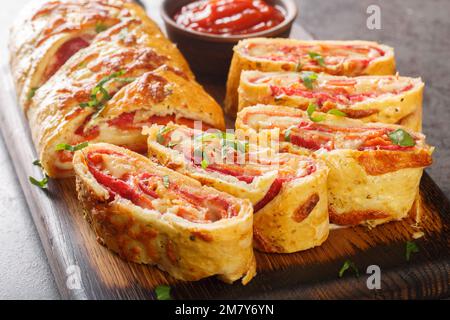 Cuisine italienne Pizza roll stromboli avec fromage, salami et tomates à proximité sur le panneau de bois sur la table. Horizontale Banque D'Images