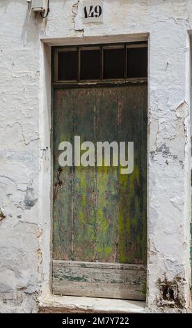 Une vieille porte peinte en vert vieilli dans un mur blanc sur l'île espagnole de Minorque Banque D'Images