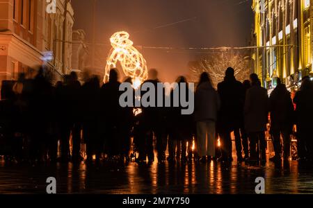 Silhouettes floues des gens et feu brûlant sur le paysage urbain avec éclairage de nuit sur la place de la ville. Ukraine Zhytomyr 22 novembre 2022 Banque D'Images