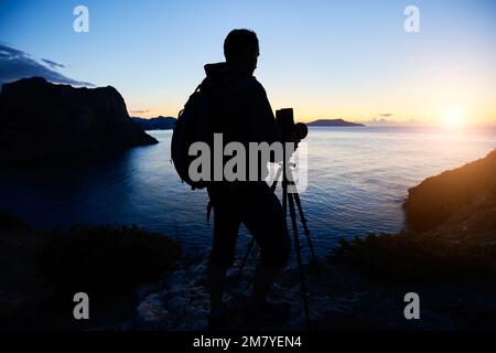 Silhouette de photographe au sommet de la montagne, sur fond de coucher de soleil. Photographe de la nature en action. Filmer la photographie analogique Banque D'Images