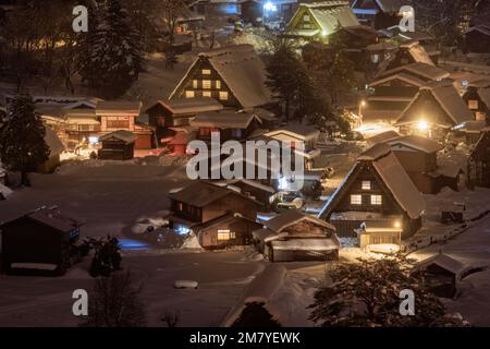Lumières colorées du petit village de montagne dans un paysage hivernal enneigé la nuit Banque D'Images