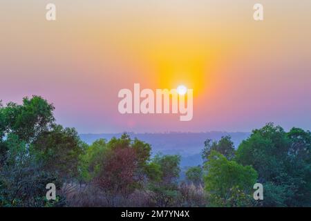 Un coucher de soleil sur une montagne. Les rayons du soleil qui brillent sur les sommets créent une gamme de couleurs, allant des oranges chaudes et jaunes aux violets et bleus frais. Banque D'Images